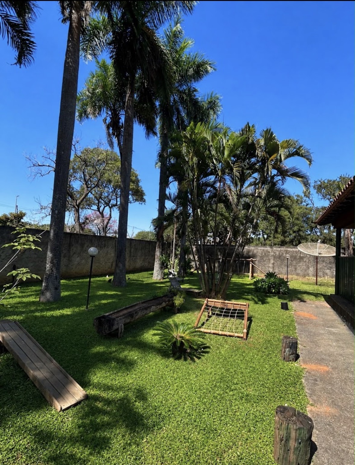 Área verde da Vivenda Montessori com árvores e brinquedos de madeira